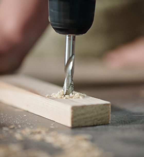 Drilling plank at workplace Close-up of unrecognizable carpenter drilling wooden plank to make holes at workplace