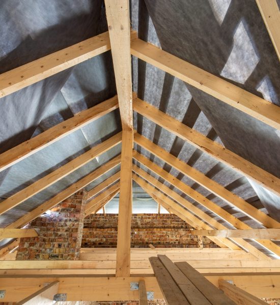 Attic of a building under construction with wooden beams of a roof structure and brick walls. Attic of a building under construction with wooden beams of a roof structure and brick walls.
